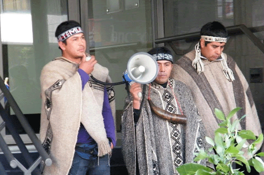 Three Mapuches, one with a loudspeaker