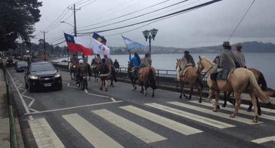 A group of Mapuche women on horses on a road