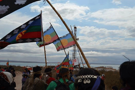 A group of Mapuches with flags near an oil field 