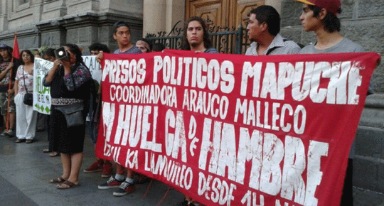 A crowd of Mapuches, four holding a large banner