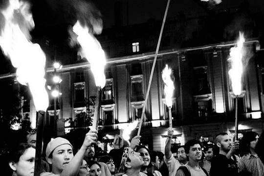 Black-and-white photo of a group of Mapuches carrying Olympic-style torches