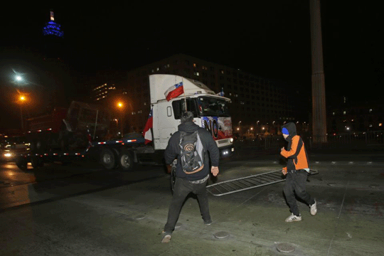 Demonstrators try to stop a caravan of trucks as they drive into Santiago, Chile, Thursday, Aug. 27, 2015
