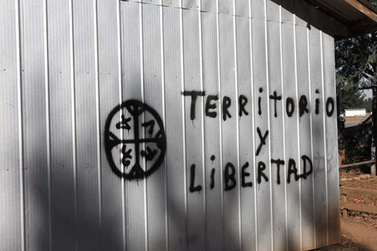 "Territorio y Libertad" daubed on a wall with the Mapuche symbol next to it