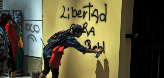 A youth doing some pro-Mapuche graffiti on a yellow wall